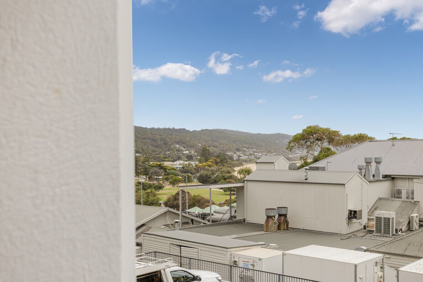 A building with a flat roof, large windows, and a view of a hilly landscape.