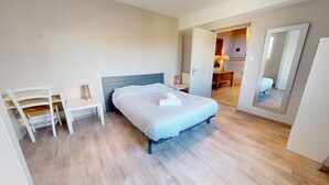 Un dormitorio con cama, mesita de noche, silla y espejo.