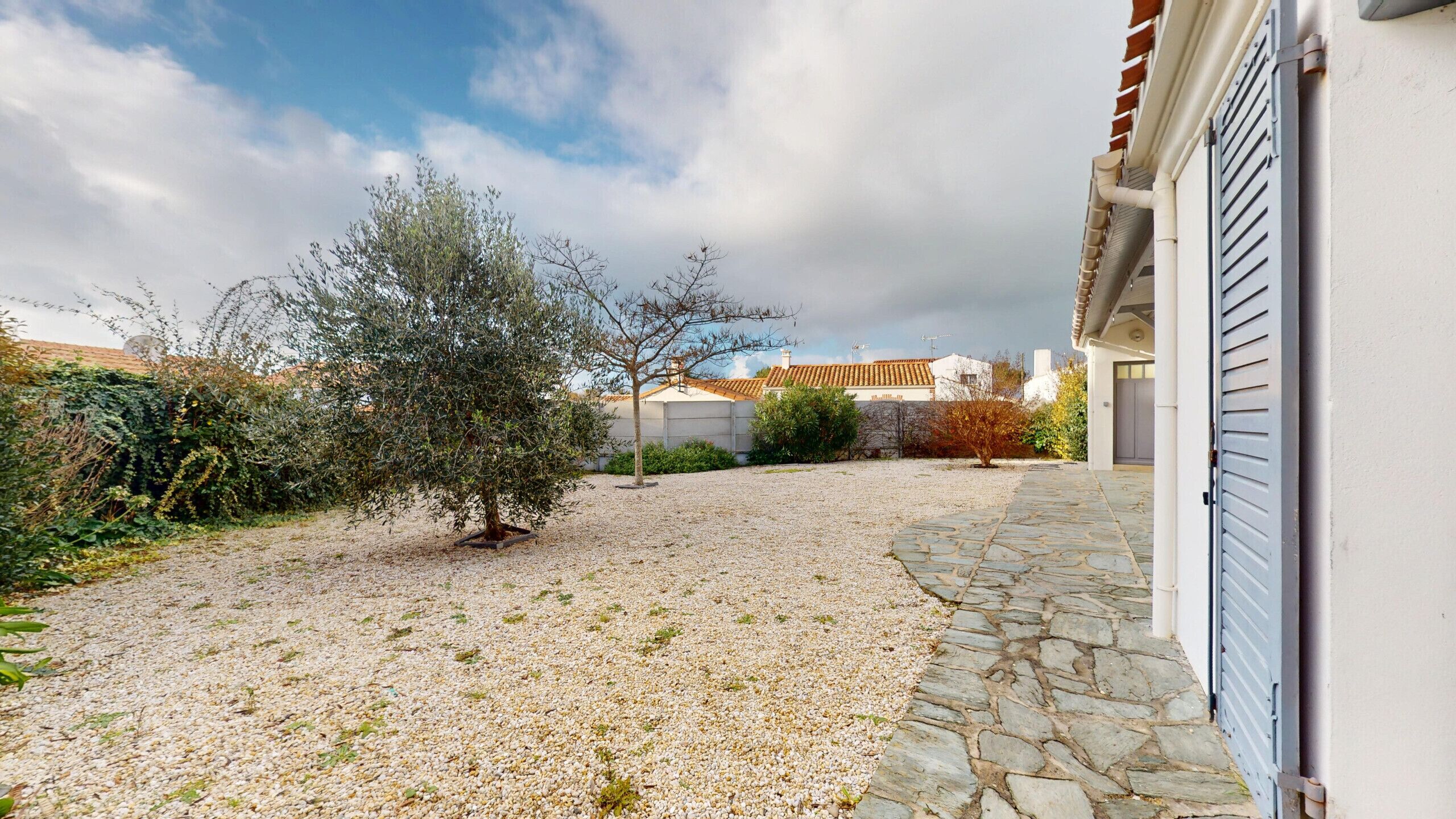 A gravel driveway leading to a house with a stone pathway.