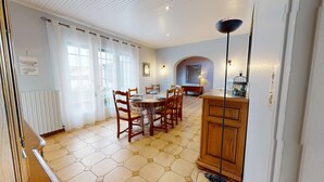 Un comedor con suelo de baldosas hexagonales, sillas de madera, una mesa de madera y un armario.