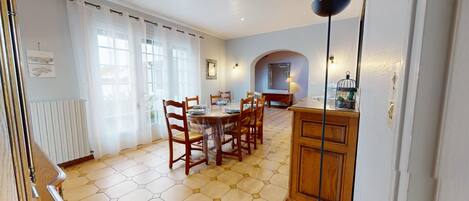 Un comedor con suelo de baldosas hexagonales, sillas de madera, una mesa de madera y un armario.