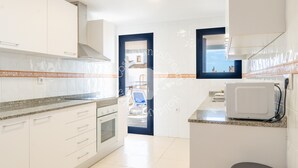A modern kitchen with white cabinets, a microwave, and a stove. - CostaBlancaDreams - Apartment Turis in Calpe (Calpe)