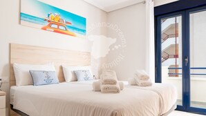 A hotel room with a bed, pillows, a painting of a boat on the wall, and a view of a balcony. - CostaBlancaDreams - Apartment Turis in Calpe (Calpe)