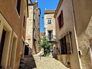 A narrow cobblestone street flanked by historic stone buildings with balconies and shutters. - Le 6 Grande Rue - Renovated Townhouse with Terrace and Garden (Saint-Gengoux-le-National)