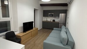 A modern living room with a grey sofa, a TV on a wooden stand, and a dining table with chairs. - Adriano Space, a complete and functional apartment in the center of Modena (Modena)