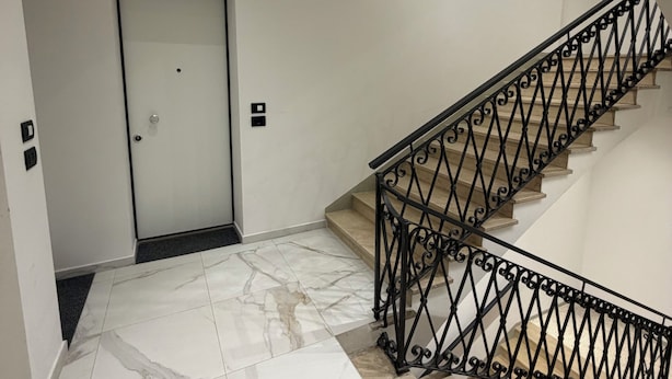A staircase with a black metal railing, a door with a frosted glass panel, and a marble-tiled floor. - Adriano Space, a complete and functional apartment in the center of Modena (Modena)