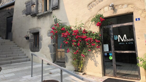 Entrada de un hotel con un cartel que dice "la Maison HOTEL & GITE".
