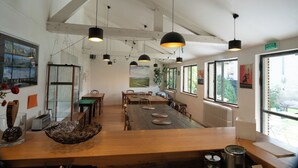 Un comedor amplio con una larga mesa de madera, lámparas colgantes y ventanas grandes que ofrecen vistas al exterior.