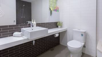 A modern bathroom with a white sink, black tiled backsplash, a toilet, and a shower.