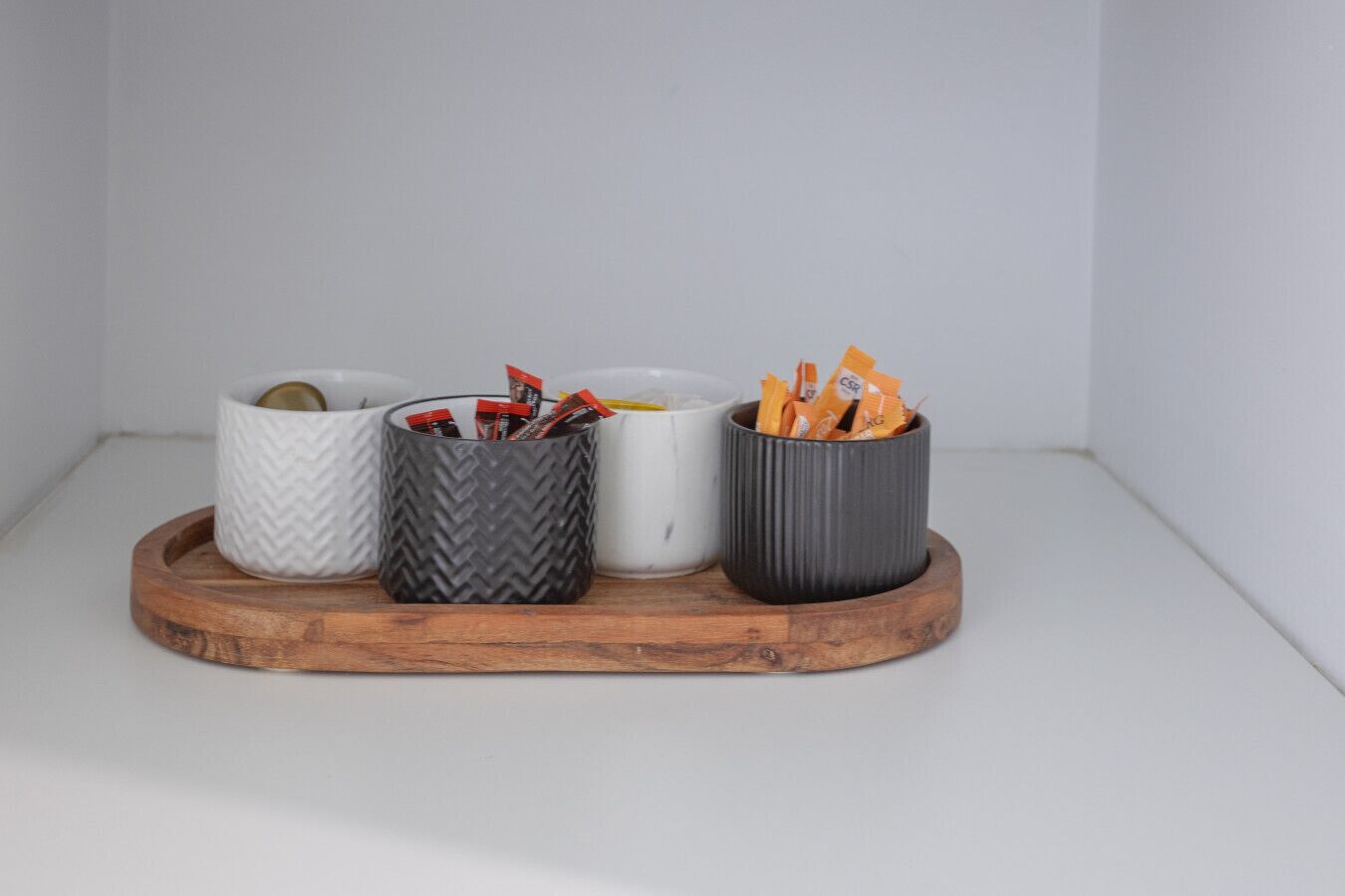 Four containers with different textures and colors on a wooden tray.