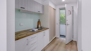 Una cocina moderna con armarios blancos, encimera de madera y horno empotrado.