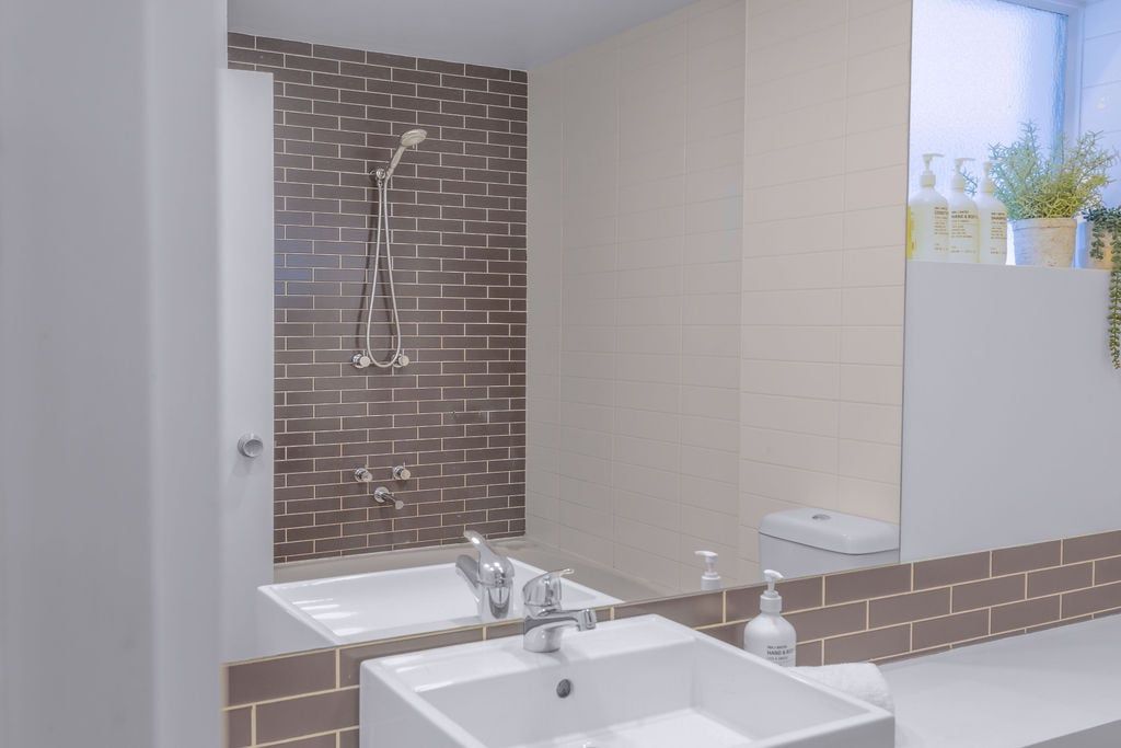 A bathroom with a shower, two sinks, and a mirror.