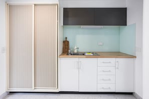 Una cocina compacta con un lavamanos, encimera de madera y armarios blancos.