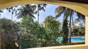 A view from a balcony with a pool and palm trees. - Villa Neesham Grande (Benaulim)