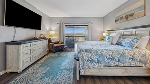 Een slaapkamer met een groot bed, een flatscreen televisie, een dressoir en een balkon met uitzicht.