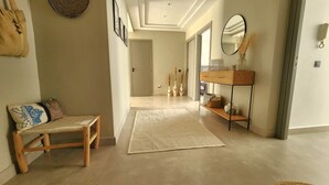Un couloir avec un banc, un tapis, une console et des tableaux encadrés accrochés au mur.