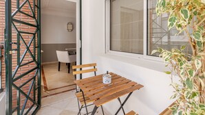 Ein kleiner Raum mit einem Holztisch und Stühlen, einem Fenster mit Aussicht und einer Tür zu einem weiteren Zimmer.