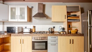 Eine Küche mit Holzausstattung, einer Edelstahl-Dunstabzugshaube, einem Backofen, einem Geschirrspüler, einer Mikrowelle und einem Kühlschrank.