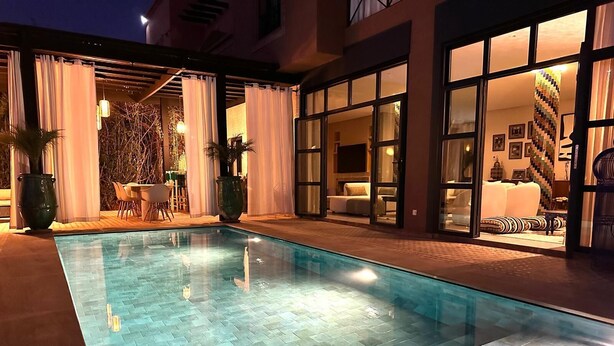 A swimming pool with tiled flooring, surrounded by a covered patio area with chairs and tables. - Dar Bassidi by IB Signature - Luxury 5BR Villa -Heated Pool & Breakfast included (Marrakesh)
