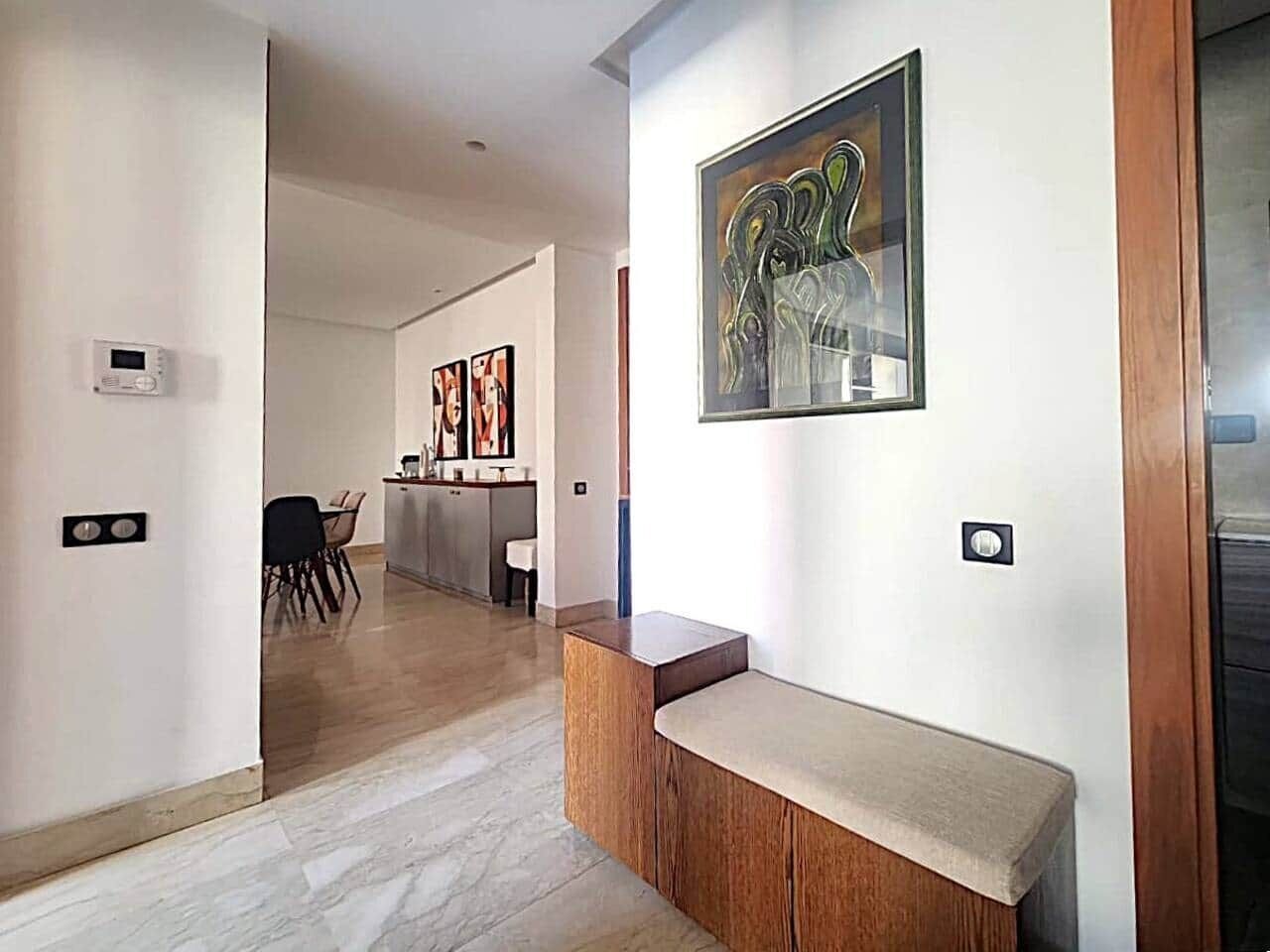 Een modern interieur met een houten bank, een schilderij en een keuken op de achtergrond.
