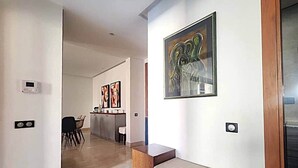 Un intérieur moderne avec un banc en bois, un tableau et un coin cuisine à l’arrière-plan.