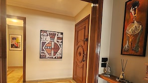 Ein Flur mit einer Holztür, einem gerahmten abstrakten Gemälde und einem Holzkonsolentisch mit einer kleinen Skulptur.