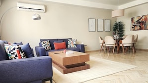Ein modernes Wohnzimmer mit einem blauen Sofa, einem Holztisch und einem Essbereich mit einer Chandelier.