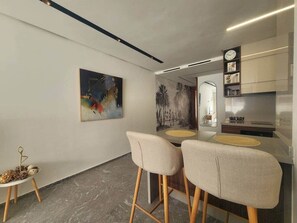 Une cuisine moderne avec un coin repas, comprenant un ensemble de tabourets de bar, un tableau et une horloge murale.