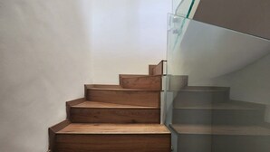 Eine Holztreppe mit Glastrennwand, die zu einer Zwischenebene führt.