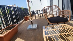 Ein Balkon mit Tisch, Stühlen, einer Topfpflanze und einem großen Sonnenschirm.