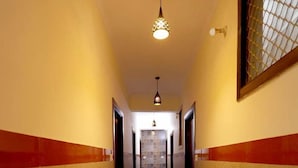 A hallway with marble flooring, red and yellow walls, and a hanging light fixture. - Basil Inn near To Taj Mahal (Agra)