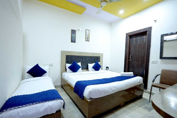 A hotel room with two single beds, a wooden headboard, a ceiling fan, and a small table.