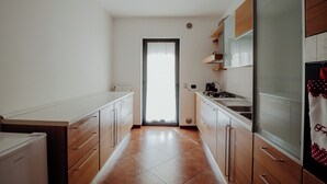 Cocina estrecha con armarios de madera, una encimera y un ventanal con puerta.