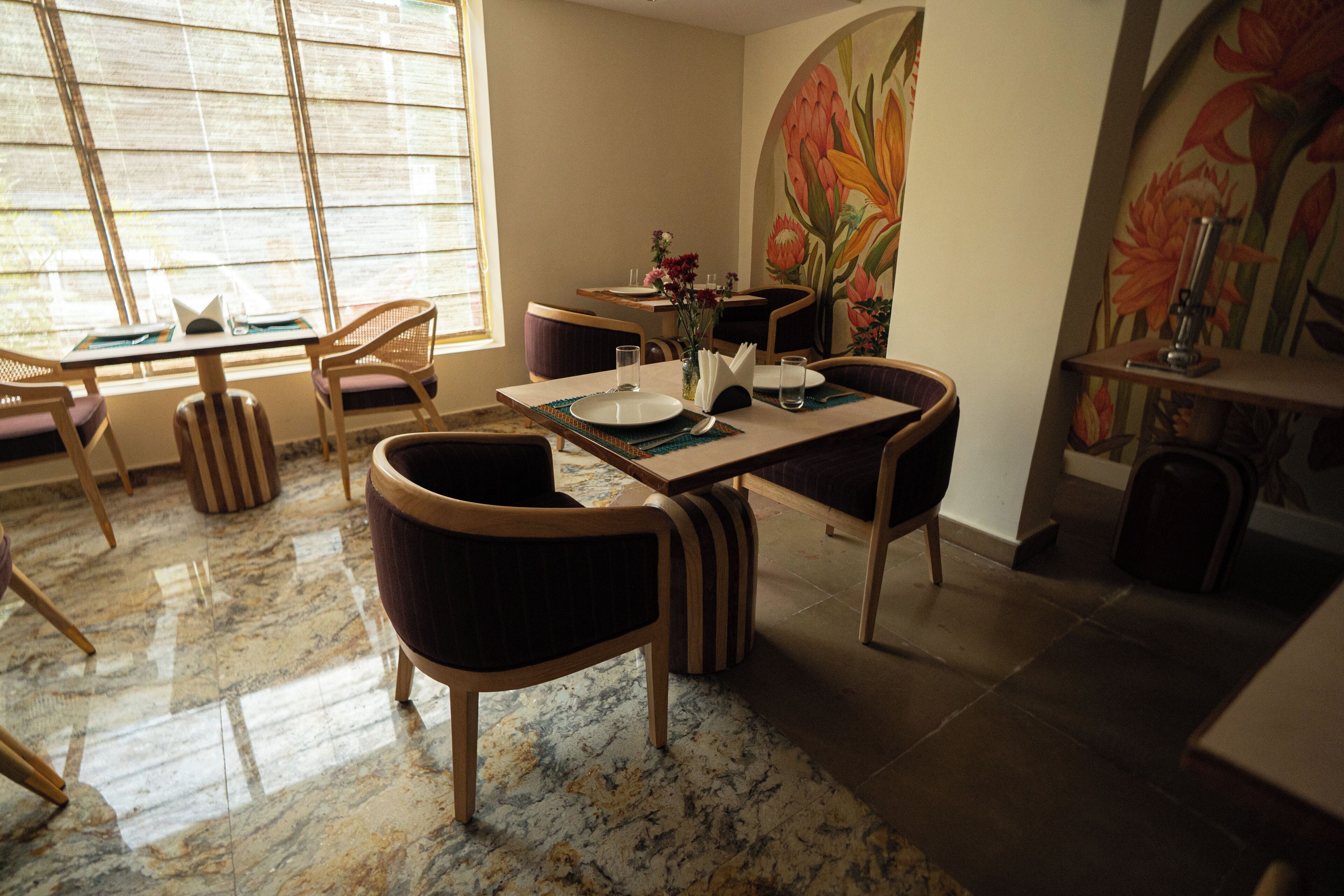 A dining area with a marble floor, wooden furniture, and a large floral mural on the wall.