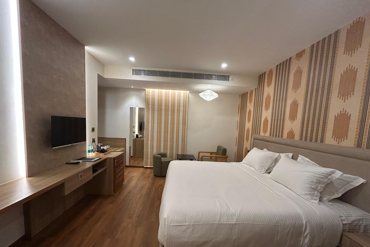 Ein modernes Hotelzimmer mit einem großen Bett, einem Schreibtisch, einem Flachbildfernseher, einem Spiegel und einer Wand mit Muster.