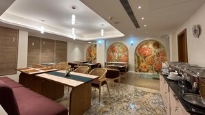 A modern dining area with a long communal table, individual seating, and a buffet station. - FERNWOOD HOTELS AND RESORTS (Bengaluru)