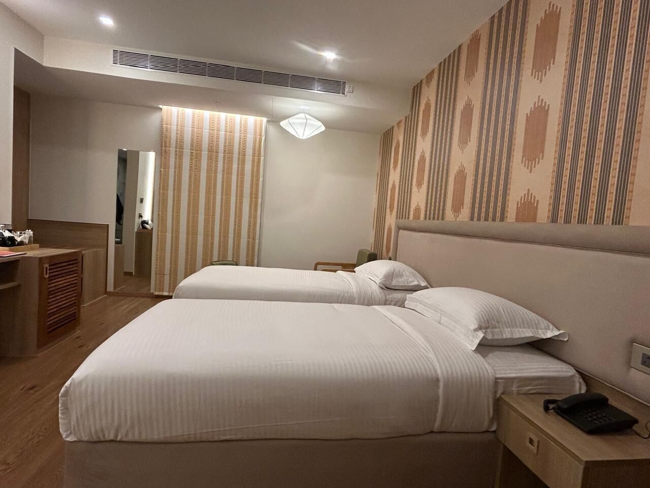 A hotel room with two beds, a desk, a phone, and a mirror.