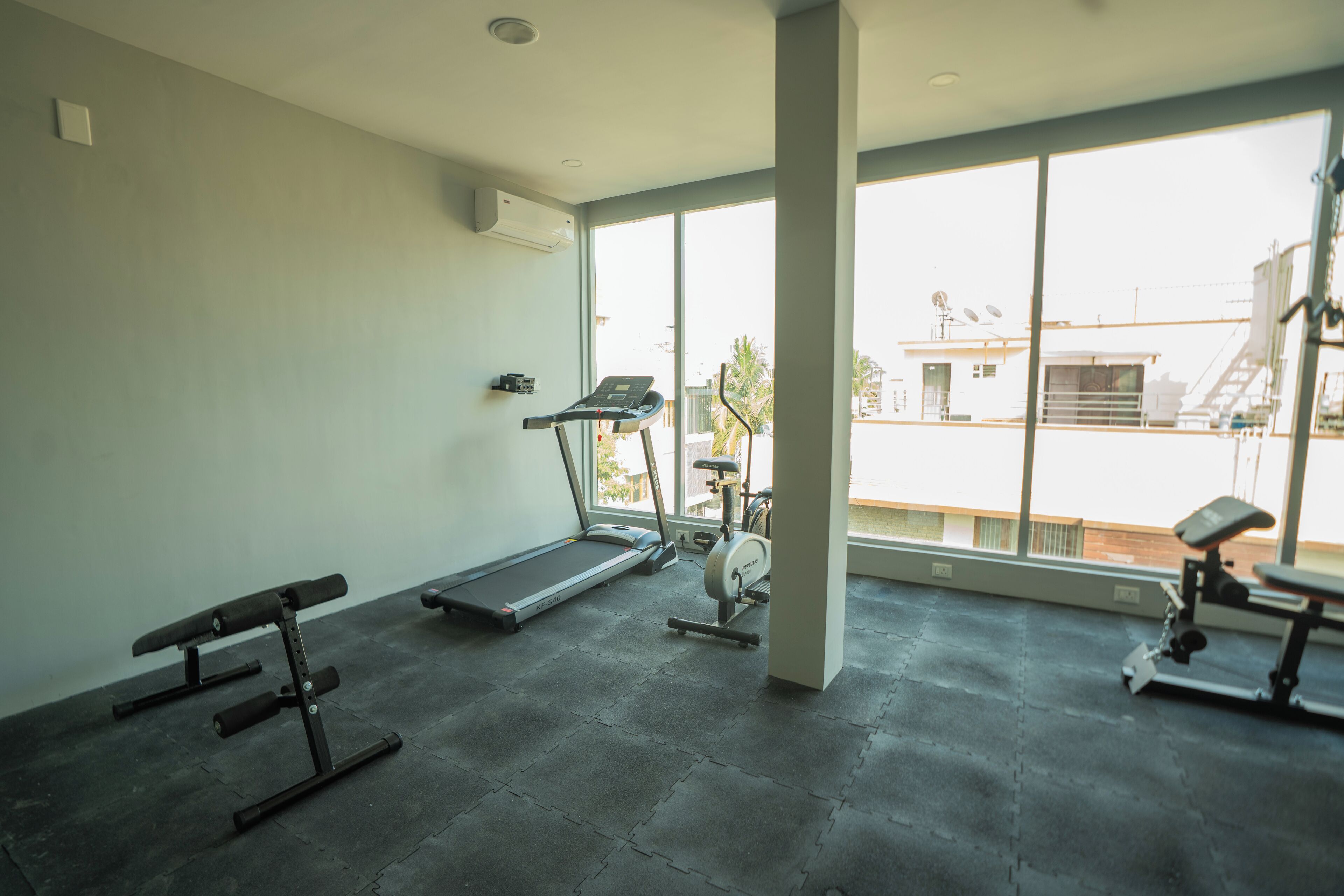 Une salle de sport équipée d’un tapis de course, d’un vélo d’appartement et d’un banc de musculation.