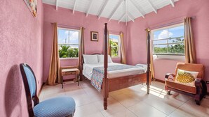 Un dormitorio con cama con dosel, una silla, una mesita y un ventanal con cortinas.