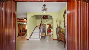 Un hallo espacioso con una escalera que conduce a los niveles superiores, un candelabro y un jarrón decorativo.