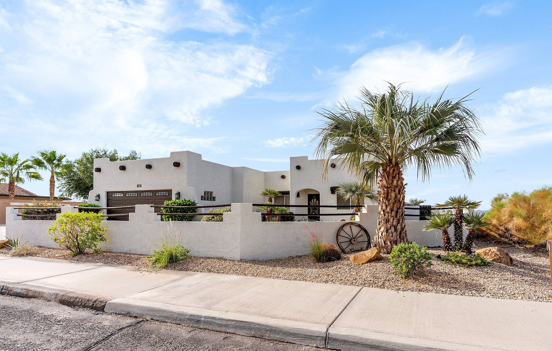 A modern building with a white facade, multiple windows, and a palm tree in the foreground.