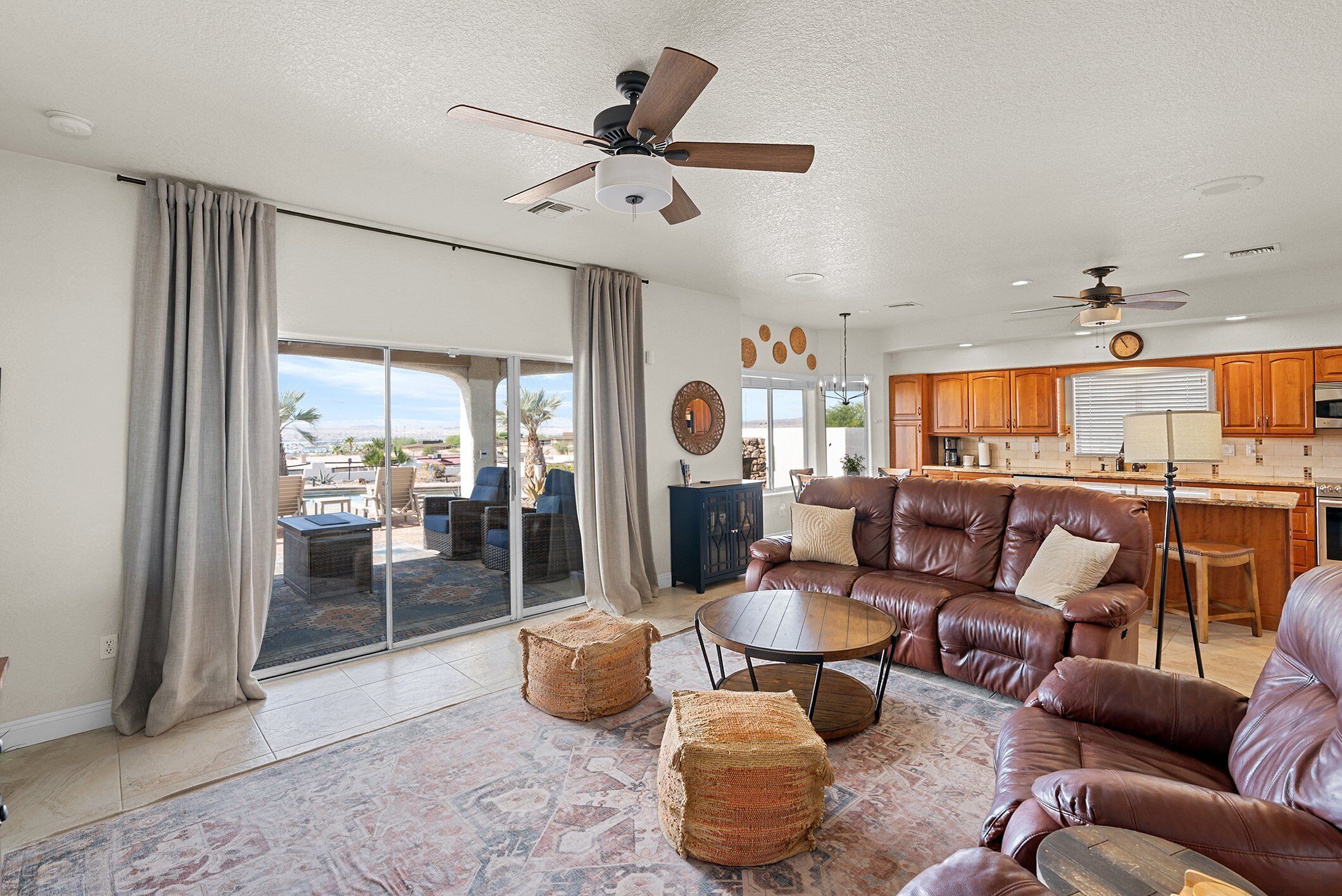 A spacious living room with a leather sofa, a coffee table, and a view through large sliding glass doors to an outdoor patio.
