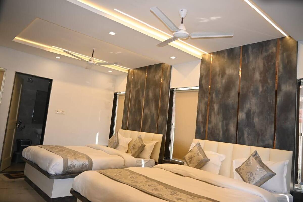 Une chambre d’hôtel avec deux lits, un ventilateur de plafond, des spots encastrés et un grand miroir.