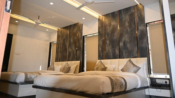 A modern hotel room with two beds, a ceiling fan, recessed lighting, and a large mirror. - Ramlala Hotel (Faizabad)
