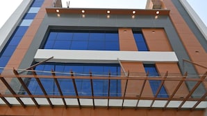 A modern building with a glass facade, large windows, and a prominent orange and gray color scheme. - Ramlala Hotel (Faizabad)
