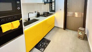 A compact kitchen with white and yellow cabinets, a black microwave, and a gas stove.