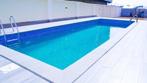 A rectangular swimming pool with a tiled edge and a metal ladder on one side.