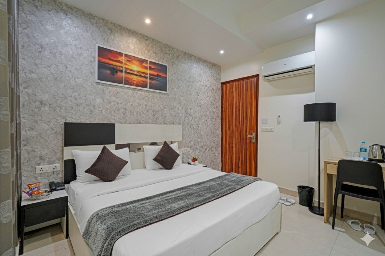 Ein Hotelzimmer mit einem Bett, einem Schreibtisch, einem Sessel, einem Nachttisch und einer Wand-Klimaanlage.