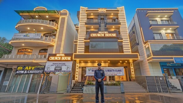 A hotel with a prominent "HOTEL CHURCH HOUSE" sign, multiple balconies, and a visible health clinic sign. - Hotel Church House - Rohini I Near Metro I Spacious Rooms I Friendly Staff I Most Preferred Hotel In Rohini (New Delhi)