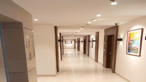 A hotel corridor with a long, straight layout, recessed lighting, and doors on both sides. - Eennra Maanikko (Krishnanagar)